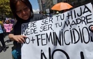 Una joven porta un cartel que pide un alto a la violencia contra la mujer